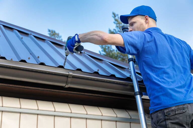 Homeowner inspecting roof shingles from a ladder on a clear, dry day with safety equipment nearby