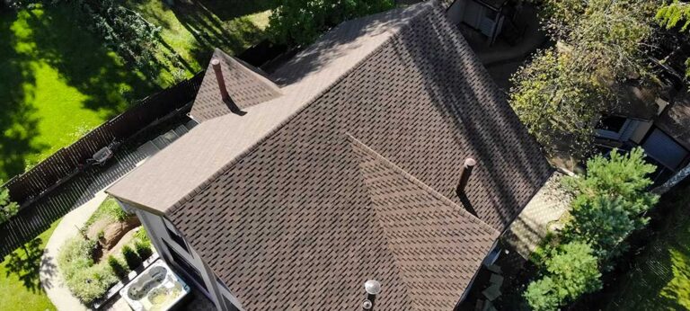 A homeowner examines lifted shingles and exposed metal flashing in a roof valley after rainfall.