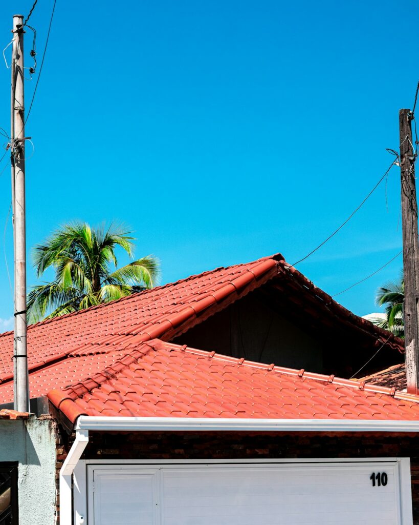 A baseball rests beside a cracked asphalt shingle near the edge of a residential roof.